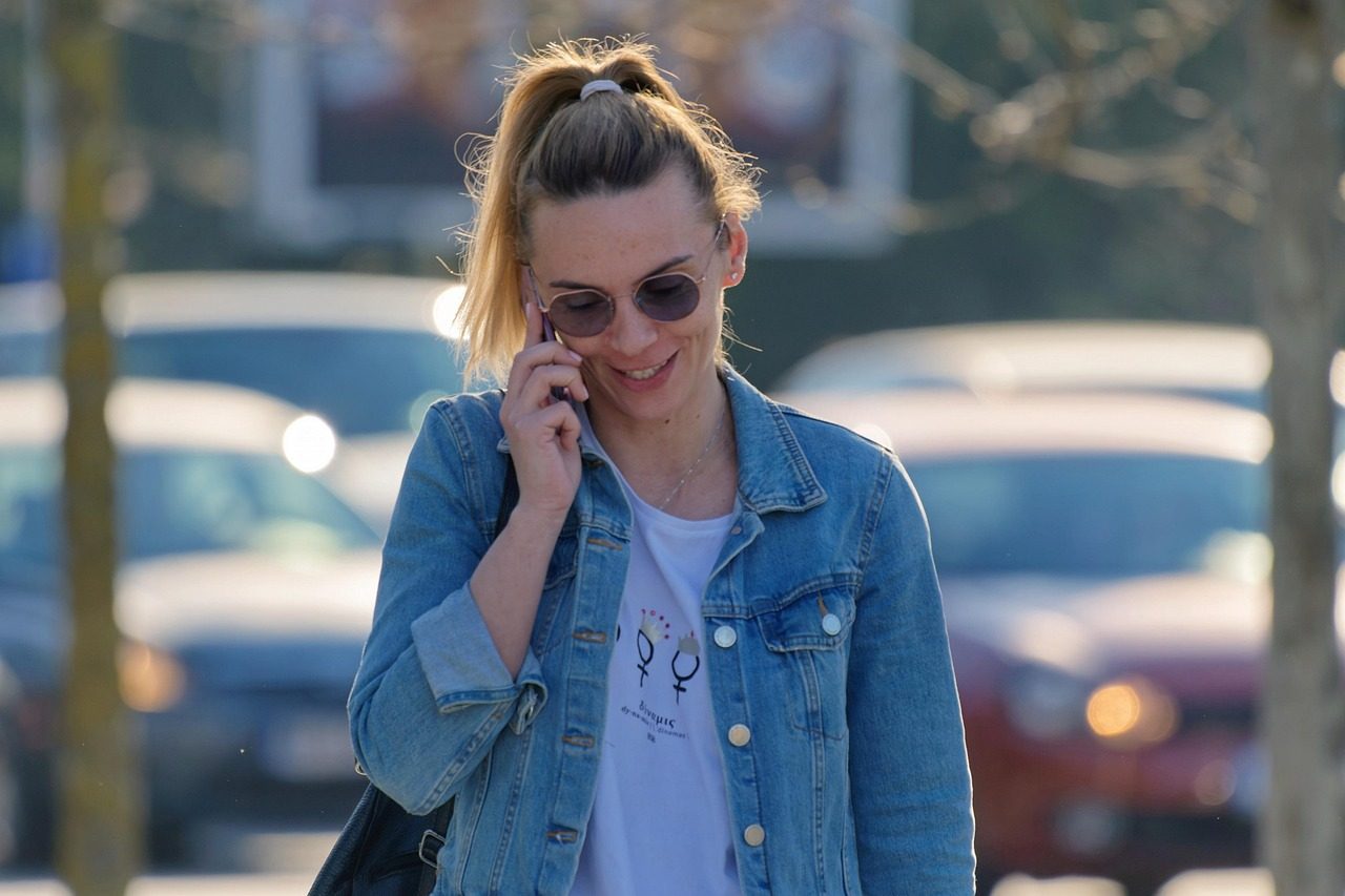 A person smiling while taking a phone call outdoors