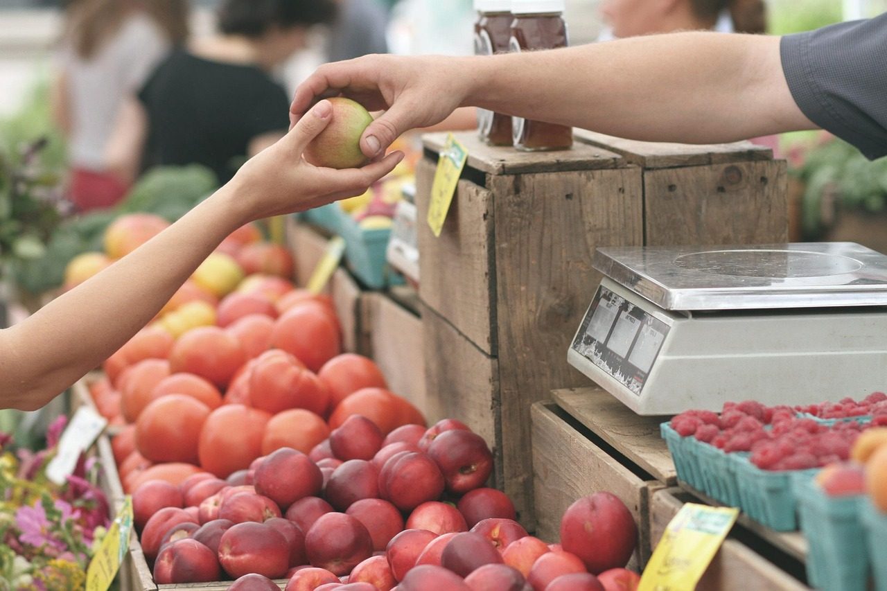 A market vendor handing fresh produce to a returning customer