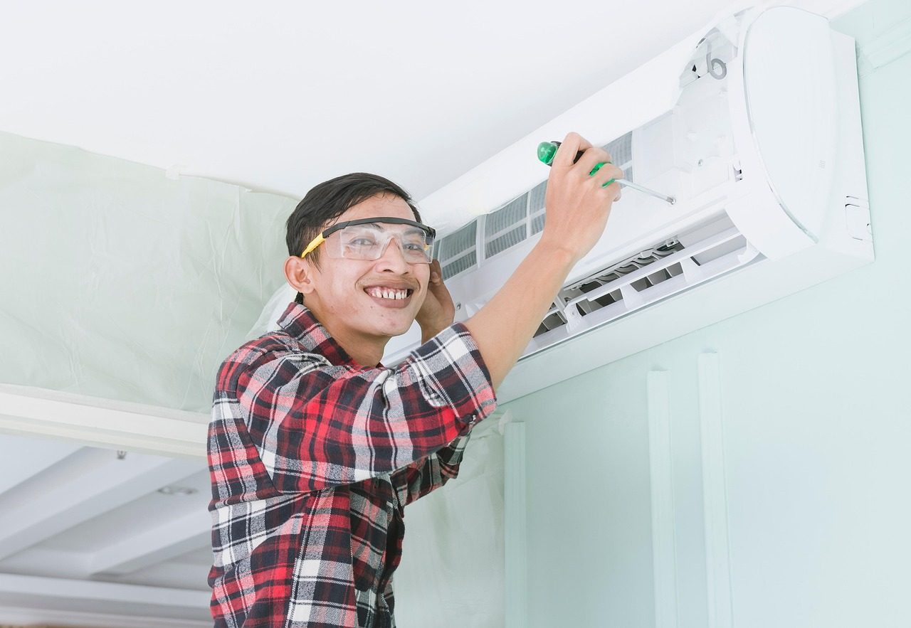 A technician servicing a wall-mounted air-conditioning unit