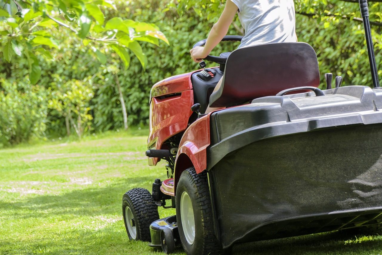 A ride-on mower cutting a green lawn