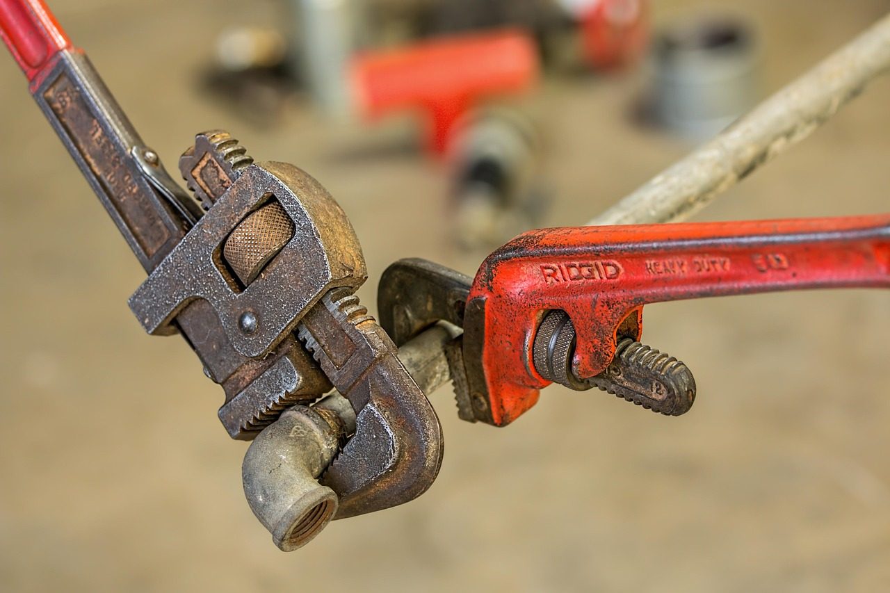 A heavy pipe wrench gripping a metal pipe during a plumbing repair
